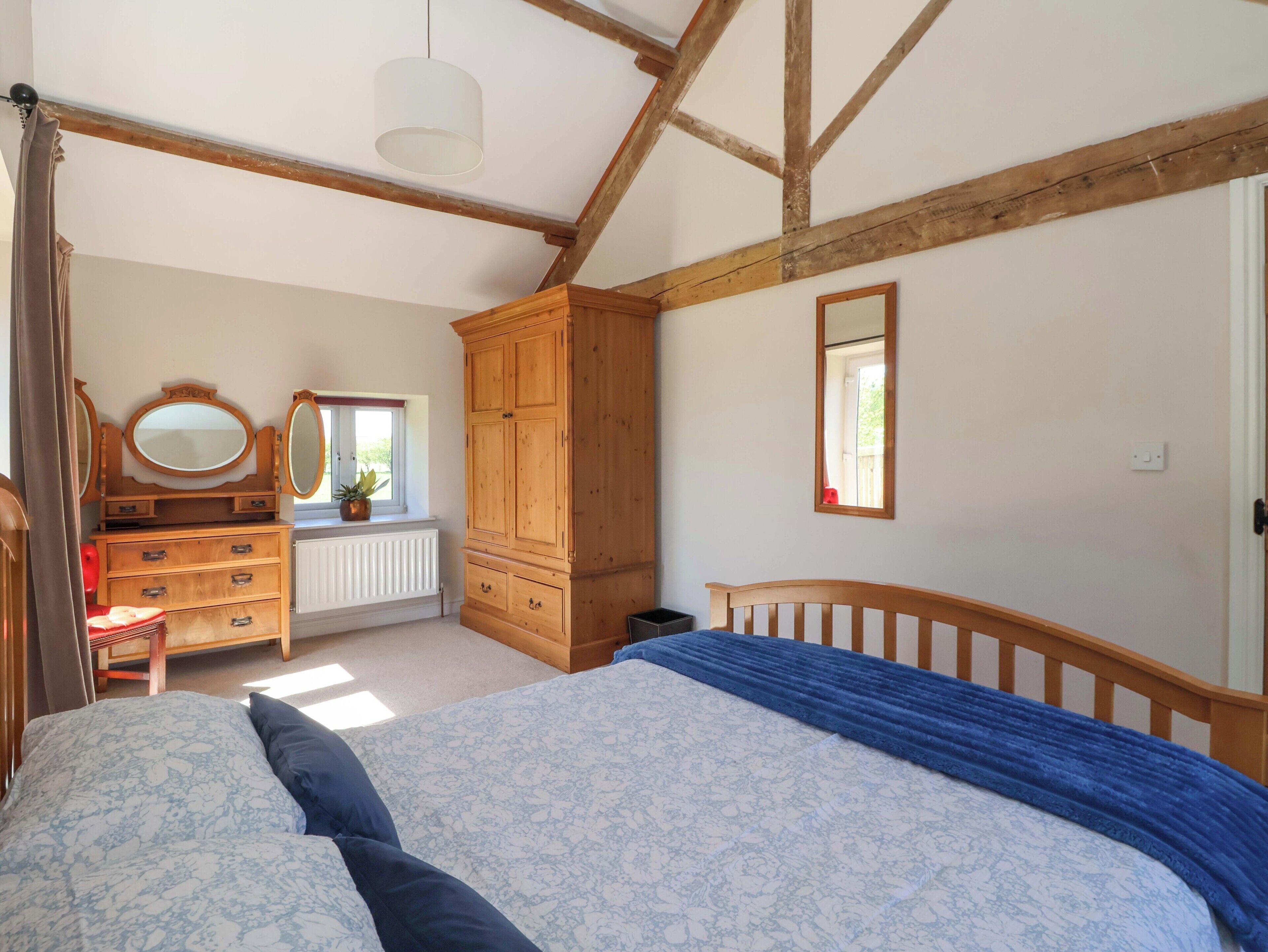 Un dormitorio con cama, armario de madera, cómoda y ventana con vistas.