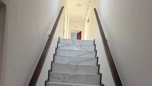 A staircase with marble steps and wooden handrails, leading to a doorway at the top. - Crest Premiums Sandton (Johannesburg)