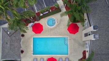 An aerial view of a swimming pool area with a pool, sun loungers, and umbrellas.