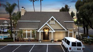 A hotel with a large parking lot, a van parked in front, and a pool in the background. - 3 Units: Pet-Friendly Kitchen Suite 2 mi to Carbon Canyon Regional Park (Brea)