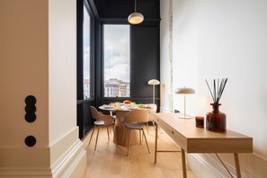 Un'area pranzo moderna con un tavolo rotondo, sedie e vista sulla città attraverso ampie finestre.