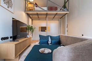 Ein modernes Schlafzimmer mit Bett, Fernseher, Schreibtisch und Balkon.