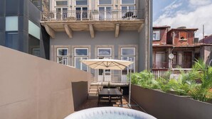 En moderne bygning med balkon, jacuzzi og en patio med bord og parasol.