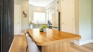 Une cuisine moderne avec un îlot central en bois, des armoires blanches et une fenêtre.