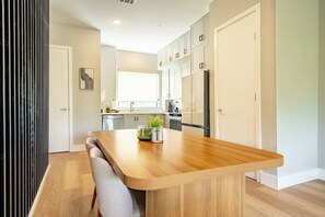 Une cuisine moderne avec un îlot central en bois, des armoires blanches et une fenêtre.