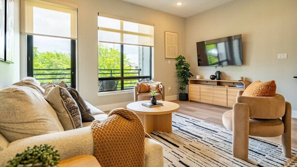Un salon moderne comprenant un canapé, des fauteuils, une table basse et un téléviseur.