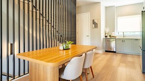 Une cuisine moderne avec des meubles blancs, une table à manger en bois et une porte-fenêtre coulissante.