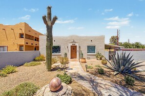A building with a stucco exterior, a wooden door, and a cactus in the foreground. - Midtown Tucson Casita | Near UofA & Dining (Tucson)