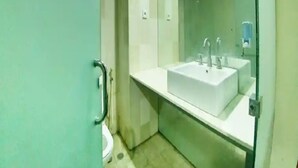 Un baño con lavamanos blanco, espejo y retrete.