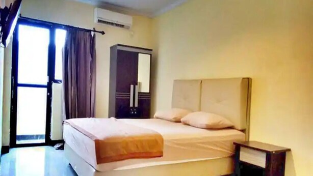 Una habitación de hotel con cama, mesita de noche y unidad de aire acondicionado.