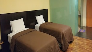 Habitación de hotel con dos camas, piso de madera y pared verde.