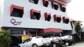 Un hotel con fachada blanca, detalles en rojo y varios balcones.