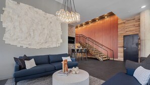 Ein modernes Wohnzimmer mit einem blauen Sofa, einem runden Couchtisch und einem großen abstrakten Wandbild.