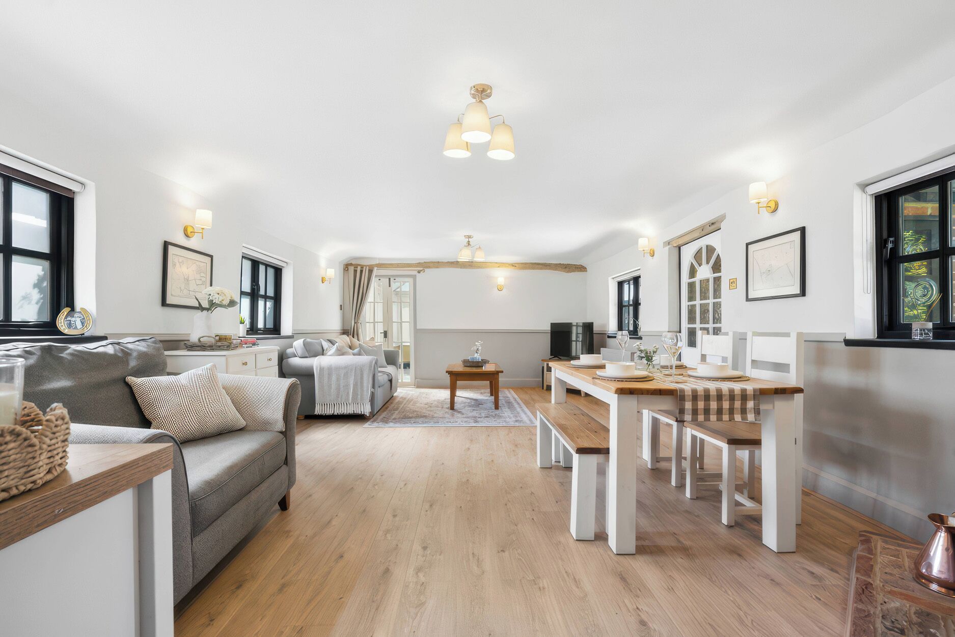 A spacious living area with a sofa, dining table, and a kitchen area in the background.