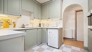 A kitchen with light green cabinets, a white refrigerator, and a checkered floor. - Five Acres Cottage (Rickmansworth)
