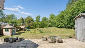 A backyard with a wooden playhouse, a slide, and a shed. - Five Acres Cottage (Rickmansworth)