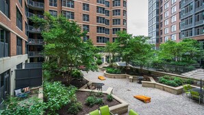 A multi-story residential building with a courtyard featuring outdoor seating, planters, and a bike rack. - Landing | Stunning 1BD, Courtyard, Gym (Washington)