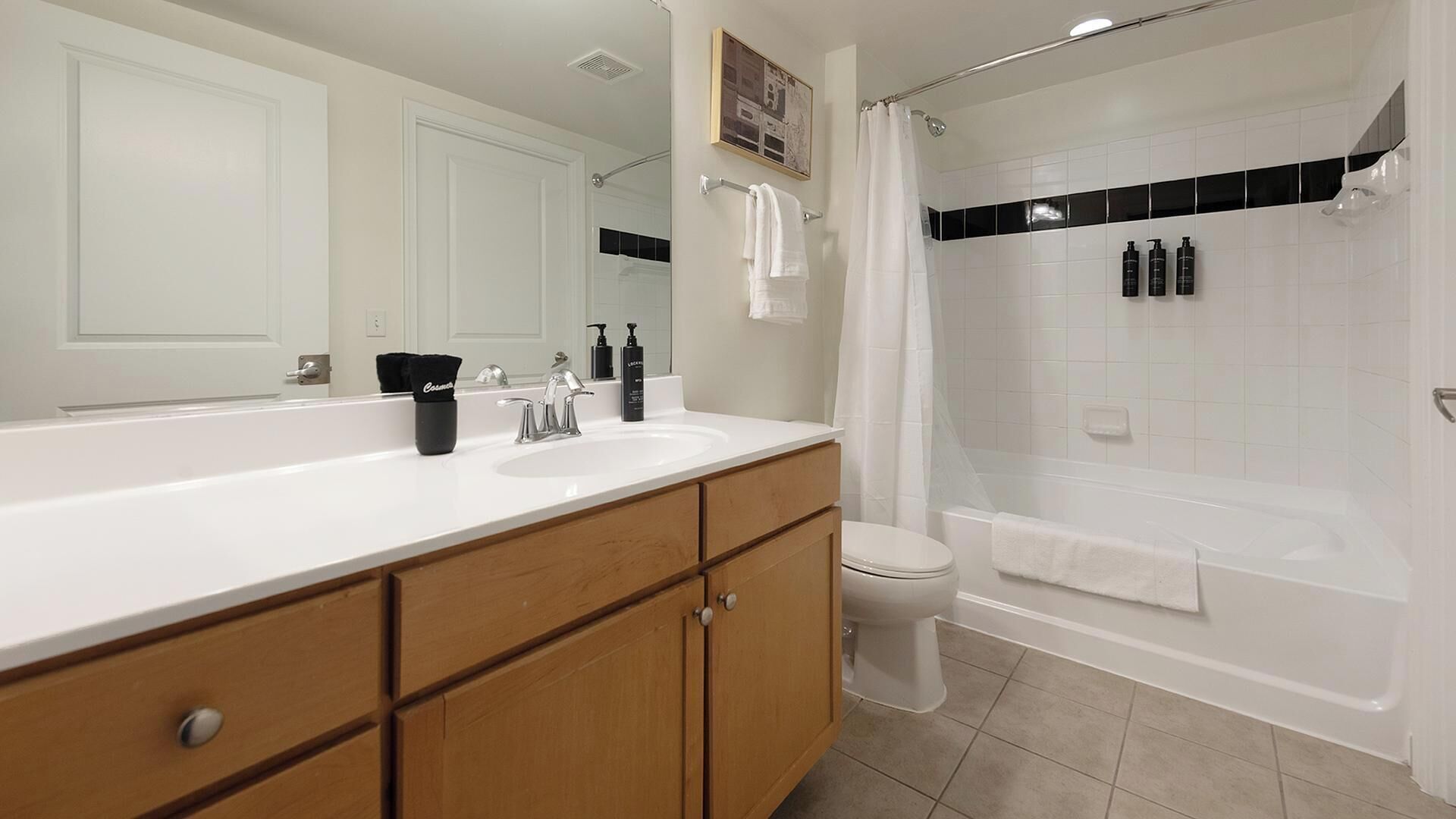 Une salle de bain moderne avec un lavabo blanc, des meubles en bois, des toilettes et une baignoire.