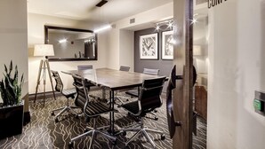 A conference room with a large table, chairs, a lamp, a mirror, framed pictures, and a sign indicating the room's purpose. - Landing | Stunning 1BD, Courtyard, Gym (Washington)