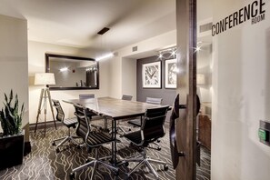 A conference room with a large table, chairs, a lamp, a mirror, framed pictures, and a sign indicating the room's purpose. - Landing | Chic 1BD, Courtyard, Gym (Washington)