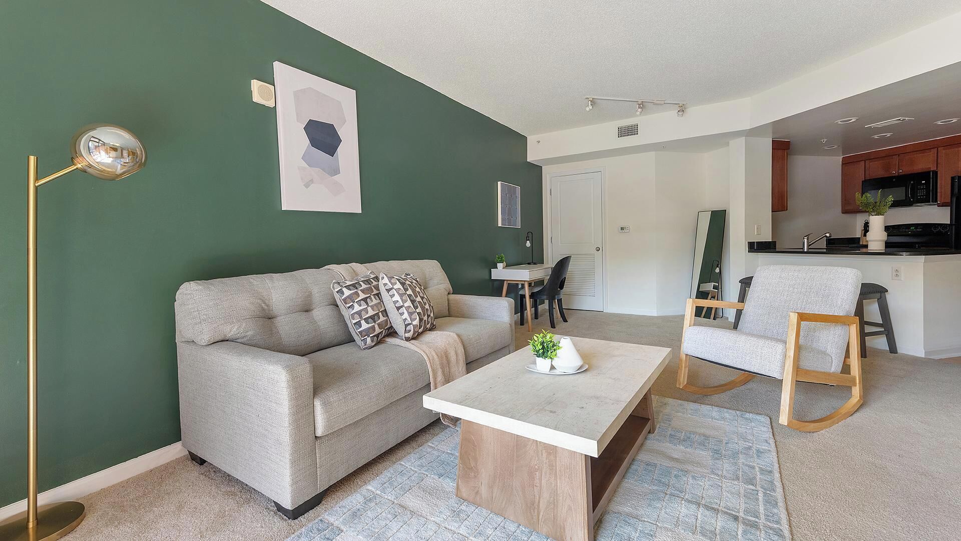 Uma sala de estar moderna com um sofá, mesa de centro e um espaço de refeições com uma cadeira e mesa.