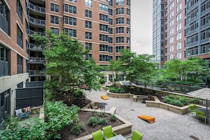 A multi-story residential building with a courtyard featuring outdoor seating, planters, and a bike rack. - Landing | Incredible 1BD, Courtyard, Gym (Washington)