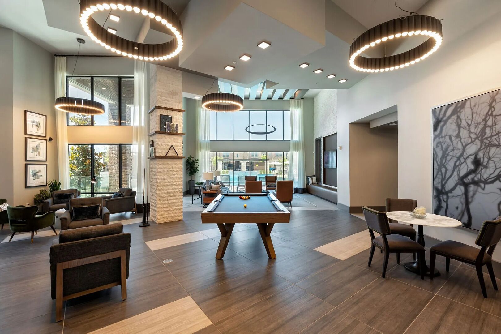 A spacious indoor area with a pool table, multiple seating arrangements, and modern lighting fixtures.