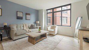 Un salon comprenant un canapé, un fauteuil, une table basse et une grande fenêtre.