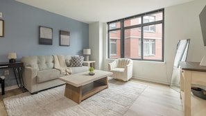 A living room with a sofa, armchair, coffee table, and a large window. - Landing | Amazing 2BD, Courtyard (Washington)