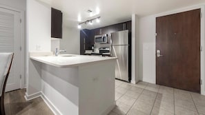 A modern kitchen with a central island, stainless steel appliances, and a dark wooden door. - Landing | Amazing 2BD, Courtyard (Washington)