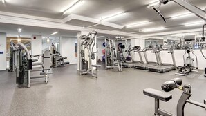 Ein modernes Fitnessstudio mit diversen Trainingsgeräten, einem großen Spiegel und einem sauberen, gut beleuchteten Raum.