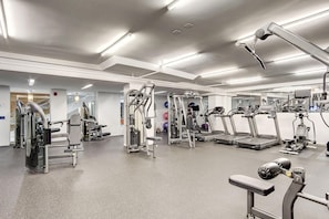 A modern gym with various exercise equipment, a large mirror, and a clean, well-lit space. - Landing | Amazing 2BD, Courtyard (Washington)