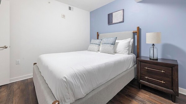 A bedroom with a bed, bedside table, lamp, and a wall-mounted picture. - Landing | Incredible 2BD, Courtyard (Washington)