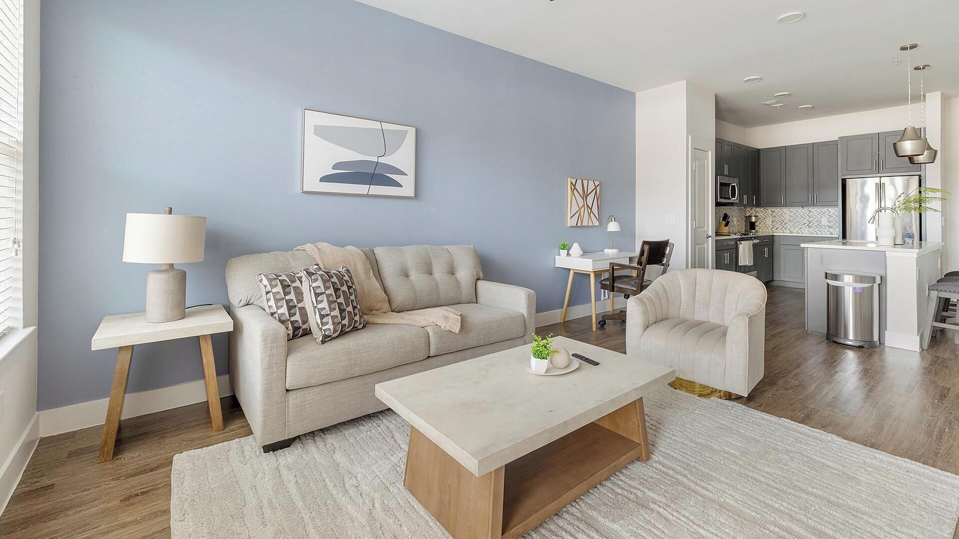 Een moderne woonkamer met een bank, fauteuil, salontafel, en een eethoek met tafel en stoelen.