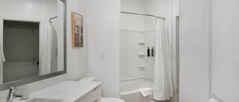 Une salle de bain moderne avec un lavabo, des toilettes et une zone de douche, le tout de couleur blanche.