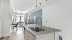Eine moderne Küche mit einer Granitarbeitsplatte, einer Edelstahlspüle und einem Deckenventilator.