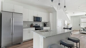 Eine moderne Küche mit Edelstahlgeräten, einer Granitarbeitsplatte und einer zentralen Kochinsel mit Barhocker.