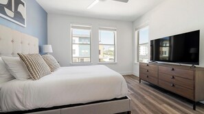 Ein Schlafzimmer mit Bett, Fernseher, Kommode und Fenstern mit Blick.