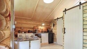 Un interior de madera con una mesa de comedor, sillas, una zona de cocina y una puerta corredera.