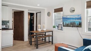 Une cuisine moderne avec des meubles blancs, un plan de travail en bois et un coin repas comprenant une table et des bancs.