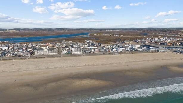 Vue aérienne d’une ville côtière avec une plage, des bâtiments et une étendue d’eau.