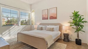 Ein Schlafzimmer mit Bett, Nachttisch, Lampe und Topfpflanze.