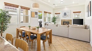 Ein modernes Wohnzimmer mit einer Couch, einem Esstisch mit Stühlen, einem Fernseher und einem Kamin.