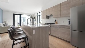 Eine moderne Küche mit einer zentralen Kochinsel, Edelstahlgeräten und Blick nach draußen.