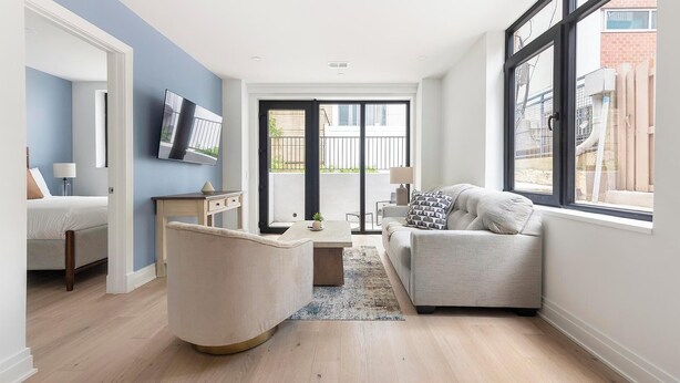 Un salon moderne avec un canapé, une table basse et un téléviseur fixé au mur.