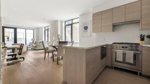 Une cuisine moderne avec des meubles en bois, un four encastré et un coin repas comprenant une table et des chaises.