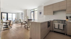 Eine moderne Küche mit Holzschränken, einem eingebauten Ofen und einem Essbereich mit Tisch und Stühlen.