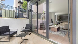 Un appartement moderne doté d’un balcon, de portes-fenêtres coulissantes, d’un coin repas et d’une cuisine.