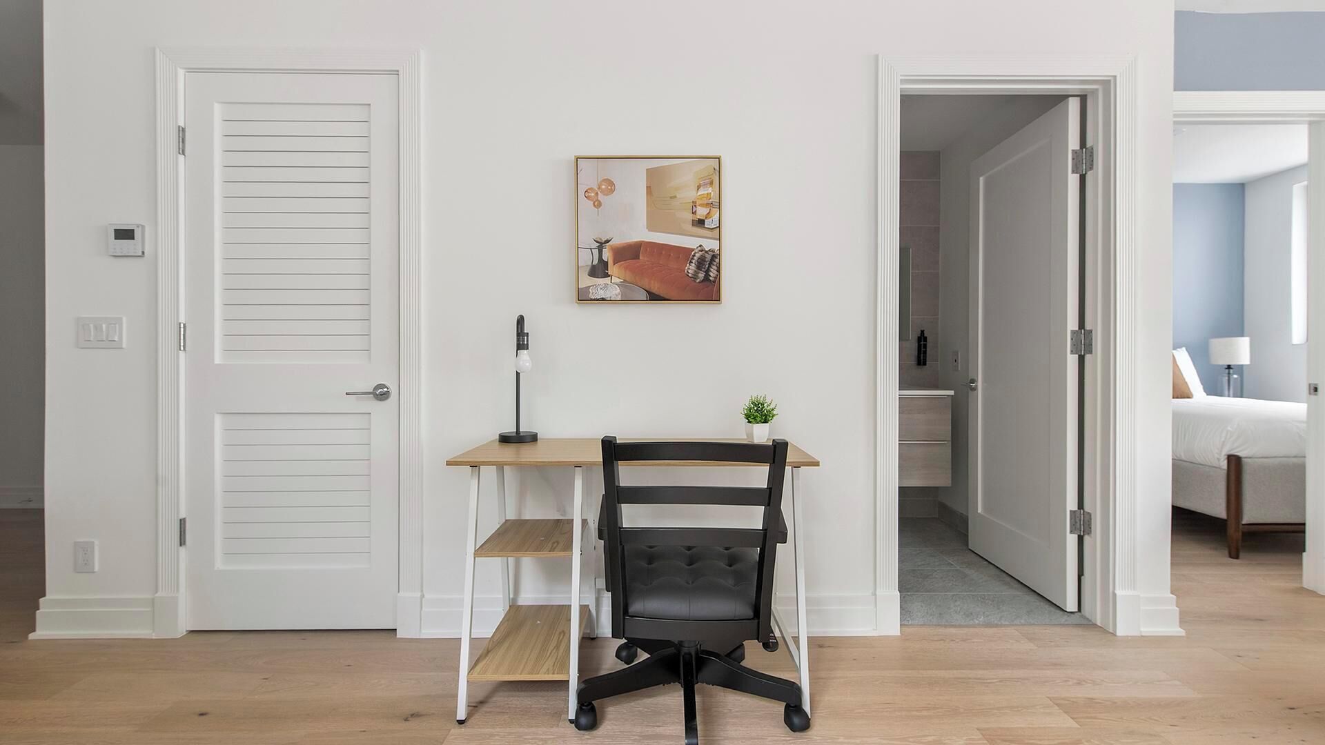 Ein Zimmer mit Schreibtisch, Stuhl und einer Tür zu einem Badezimmer.