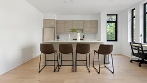 A modern kitchen with a central island, four bar stools, and a large window. - Landing | Incredible 2BD in Logan Circle (Washington)
